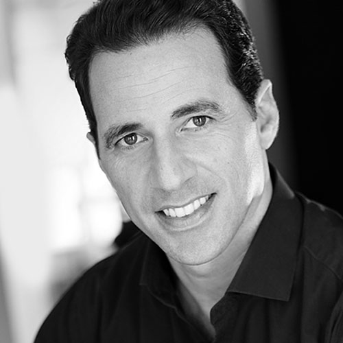 Short-haired brunette male in dark shirt smiling.