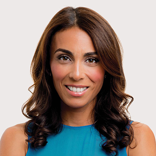 Brunette woman in sleeveless blue top smiling.